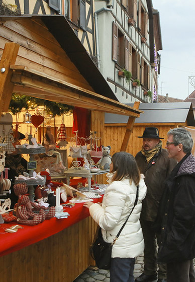 Alsatian Christmas market with traditional chalets and visitors discovering artisan stalls