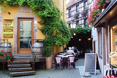 Malerische Gasse in einem elsässischen Dorf mit einem Gourmetrestaurant und Terrasse
