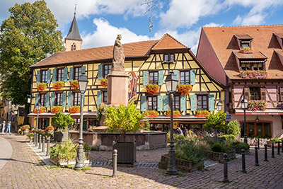 Balcons fleuris de géraniums sur une maison à colombages dans un village fleuri d'Alsace au printemps